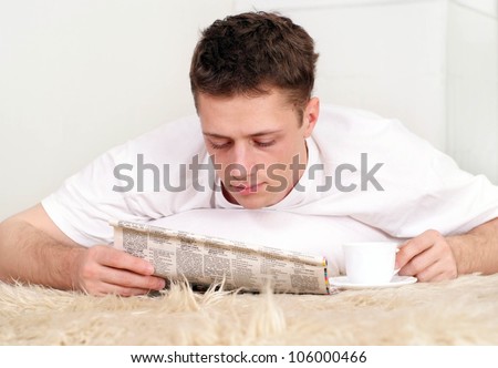 Beautiful Caucasian man lying on the mat with the paper on a light background