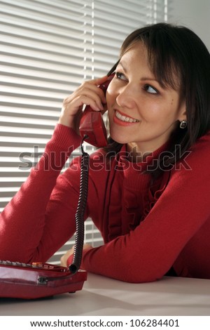 Pretty Caucasian woman sitting with a phone on a light background