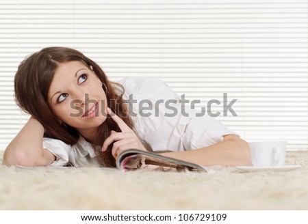 Luck Caucasian woman lying on a carpet with a magazine and cup