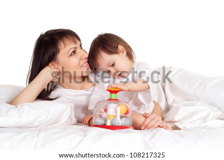 A nice Caucasian mother with her daughter playing with a toy in bed
