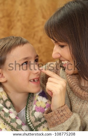 A beautiful nice mother with her son sitting on the couch on a light background