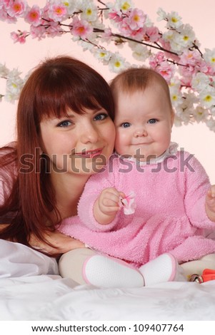A luck Caucasian mother with her daughter lying in bed on a light background