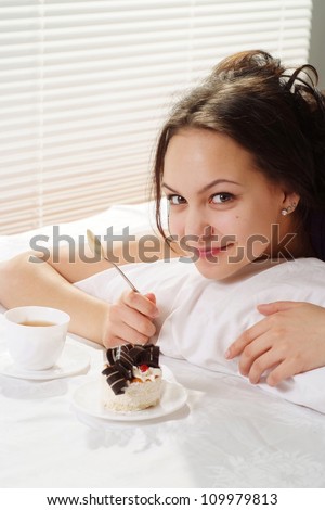 Luck Caucasian woman lying in a bed of cake on a light background