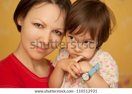 Young woman hugging a little pensive girl