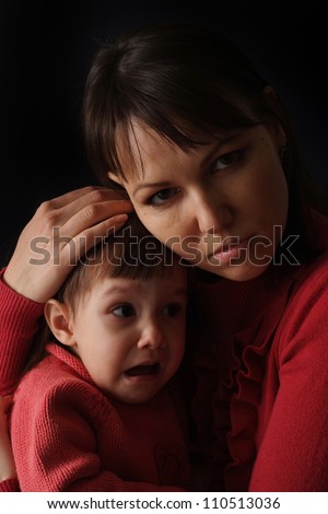 A happy Caucasian mother with a sad crying daughter on a dark background