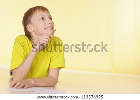 Cheerful boy in a yellow T-shirt has a good time at home