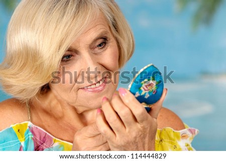 beautiful elderly woman looks in the mirror on a blue background