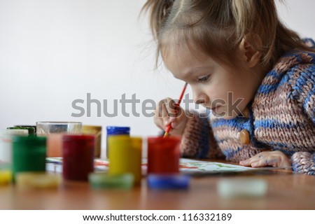 portrait of a cute baby draws paint in the room