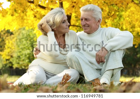 beautiful elderly couple sitting in autumn park