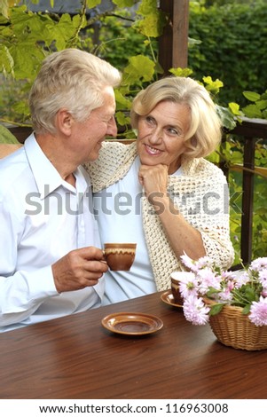 Happy beautiful elderly people drink tea at the table