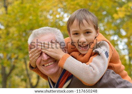 Happy grandfather and grandson playing in autumn park