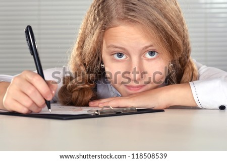 portrait of a nice girl studying at a table on a light background