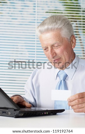 elderly man sitting at the laptop on a light background