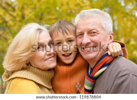 elderly couple and grandson posing in autumn park