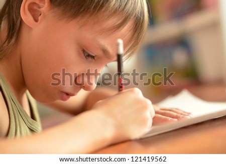 nice boy sitting at a desk writing