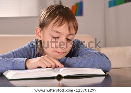 nice little boy sitting at a desk with book