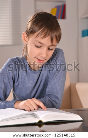 nice little boy sitting at a desk with book