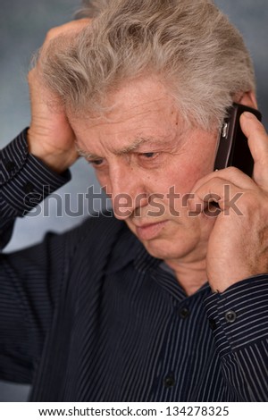 portrait of a sad older man calling on a gray background