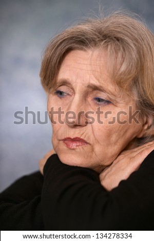 portrait of melancholy older woman in a black sweater on a gray background