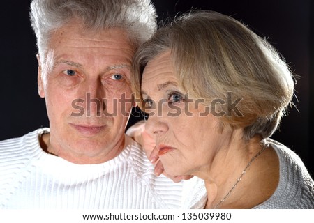 close-up portrait of an elderly couple embracing on a black background