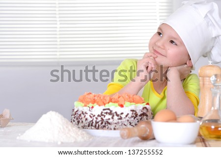 lovely girl in a chef\'s hat with a beautiful sweet cake