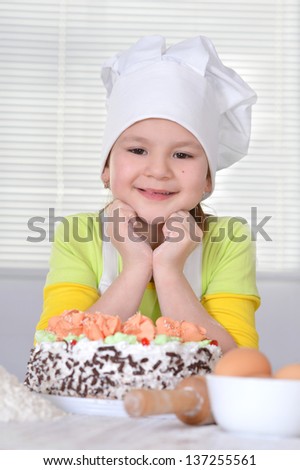 lovely girl in a chef's hat with a beautiful sweet cake