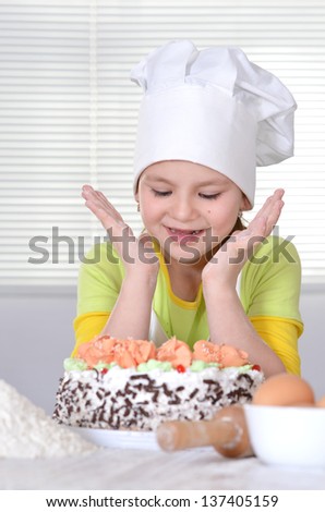 lovely girl in a chef\'s hat with a beautiful sweet cake