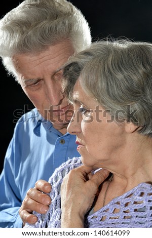Portrait of an elderly couple embracing on a black background