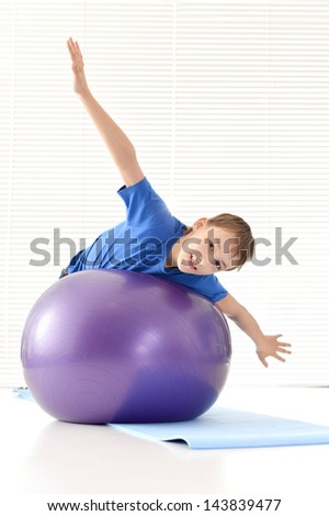 sporty young guy in a blue shirt with gymnastic ball