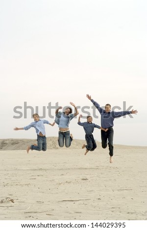 happy family of four people jumping outdoors