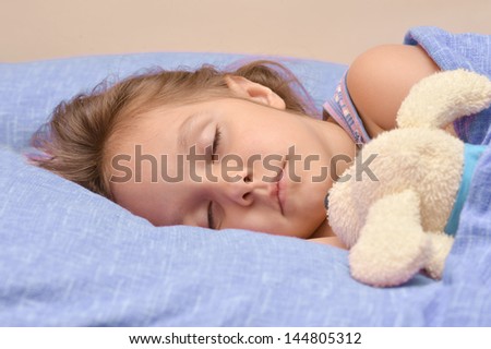cute little girl sleeping with a toy in her bed