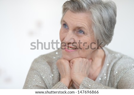Portrait of an aged woman in a gray sweater at home