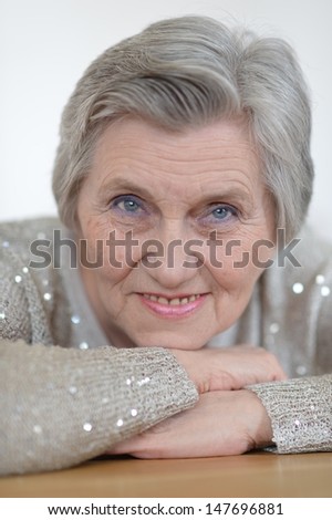 Portrait of an older woman in a gray sweater at home