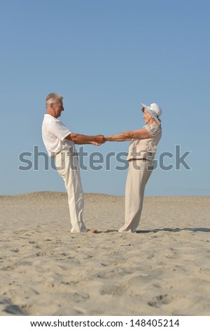old couple in love walking barefoot in the sand