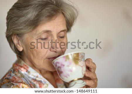 Happy old woman drinking tea in the morning at home
