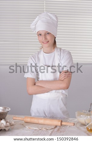 Young boy in a chef\'s hat knead dough for cookies