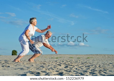 Elderly happy couple having fun in the sand together