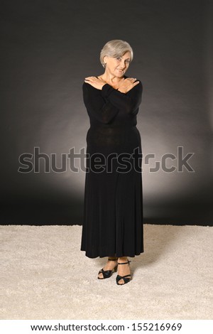 elderly woman in black dress smiling on dark background
