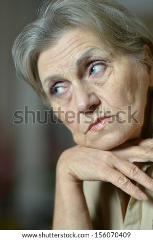 Close-up portrait of sad elderly woman on a gray background