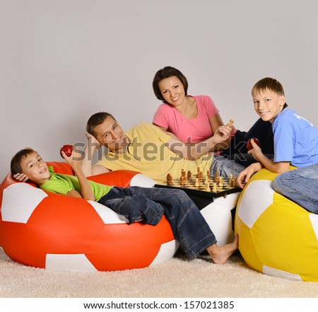 Family of four watching tv sitting on colored cushions