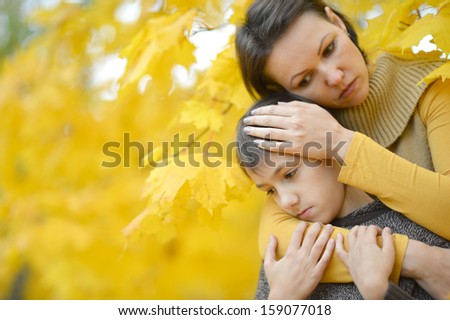 mum with the son on a walk during the fall of the leaves in the park
