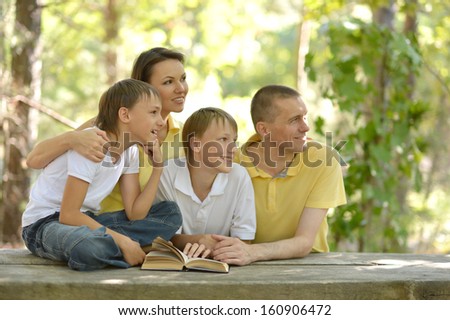 Family of four reading outdoors at table