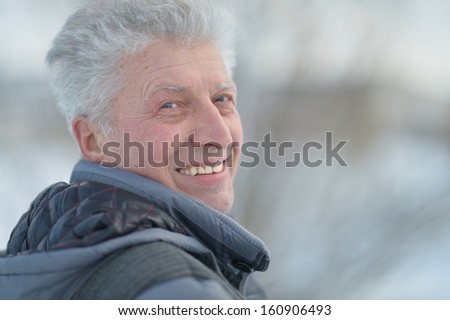 Portrait of happy elderly man against winter forest background