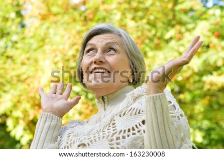 Happy elderly woman enjoying in autumn park