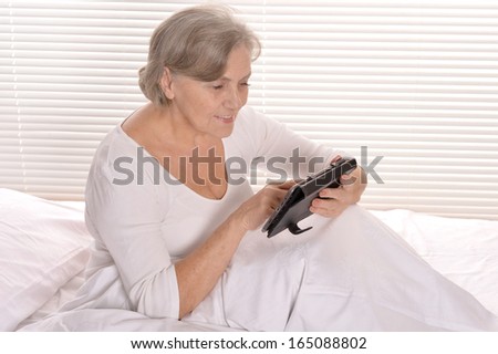Old woman lying in bed with tablet pc