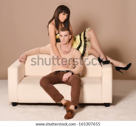 Young couple portrait sitting on sofa on beige background