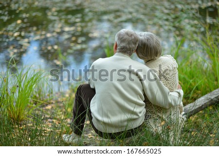 Happy senior couple sitting in summer near lake