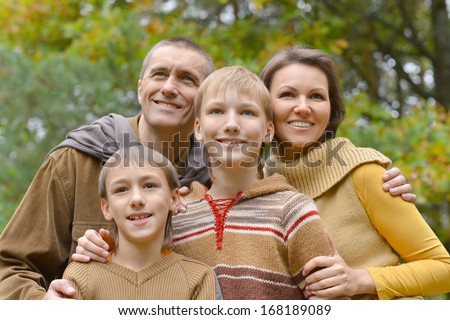 Happy family of four standing together in the park in autumn
