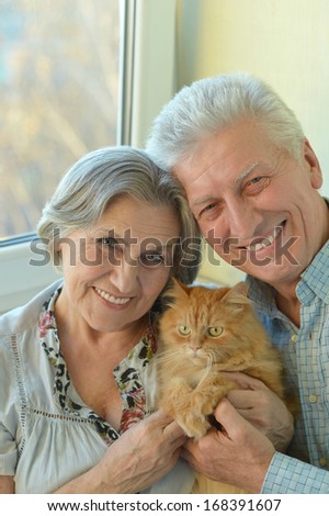 Good-looking older couple sitting at home with cat