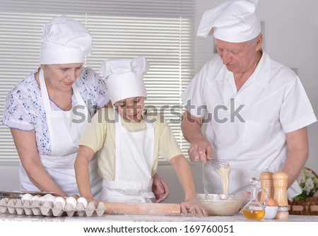An elderly couple and their grandson knead the dough for the pie together